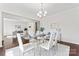 Elegant dining room featuring a glass table, white chairs, and a view to the home office at 1527 Sunflower Field Pl, Matthews, NC 28104