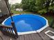 Backyard pool with blue liner surrounded by a wood deck and lush greenery, perfect for summer relaxation at 5229 Mt Holly Huntersville Rd, Charlotte, NC 28216