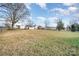 Large backyard with spacious grassy area, mature trees, and a chain link fence at 6208 Karenstone Dr, Charlotte, NC 28215