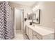 Well-lit bathroom featuring a modern vanity, neutral tones, and a stylish patterned shower curtain at 8636 Robinson Forest Dr, Charlotte, NC 28277