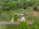 Aerial view of home with long drive, green lawn, and surrounded by mature trees and a quiet road at 1410 Mays Chapel Church Rd, Newton, NC 28658