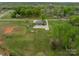 Aerial view showcases the property with an expansive green lawn, mature trees, and surrounding landscape at 1410 Mays Chapel Church Rd, Newton, NC 28658