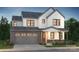 Two-story farmhouse with gray garage door, stone accents, and landscaping at 15004 Brownleigh Ln, Huntersville, NC 28078