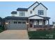 Charming two-story home featuring white siding, a stone facade, and an attached two-car garage at 15004 Brownleigh Ln, Huntersville, NC 28078