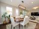 Dining room with a wood table, six chairs, modern light fixture, and view to the living room at 2812 Ensemble Ct, Charlotte, NC 28262