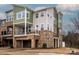 Modern three-story townhome featuring a stone base, multiple balconies, and a two-car garage at 2812 Ensemble Ct, Charlotte, NC 28262