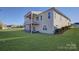 Spacious backyard of two-story home with upper deck, lower patio and a large, green lawn on a sunny day at 45528 Misty Bluff Dr, Charlotte, NC 28278