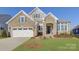 Charming home featuring stone accents, a manicured lawn, and a two-car garage, bathed in sunlight at 45528 Misty Bluff Dr, Charlotte, NC 28278