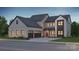 Two-story farmhouse with gray siding, stone accents, and a three-car garage at 13944 Roosevelt Grove Dr, Huntersville, NC 28078