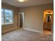 A cozy bedroom with neutral carpeting, an ensuite bath, and a window with neighborhood view at 18140 Kalabash Rd, Charlotte, NC 28278