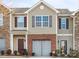 Two-story townhome with brick and stone accents, two-car garage, and landscaping at 9408 Hamel St, Charlotte, NC 28215