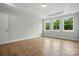 Bright bedroom with tray ceiling, hardwood floors, and natural light from three windows at 4003 Grace Pointe Dr # 99, Wesley Chapel, NC 28079