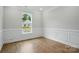 Living room features wood-style flooring, a window and traditional wainscotting at 4003 Grace Pointe Dr # 99, Wesley Chapel, NC 28079