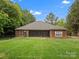 Large backyard featuring a well-maintained lawn, mature trees, and brick home with screened-in porch at 416 Zelkova St, York, SC 29745