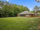 Large backyard featuring a well-maintained lawn, mature trees, and brick home with screened-in porch at 416 Zelkova St, York, SC 29745