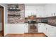 Kitchen features brick accent wall, white cabinets, stainless steel appliances, and hardwood floors at 6520 Weldon Nw Cir, Concord, NC 28027