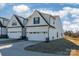 Rear view of townhome showcasing white siding, two-car garage, and yard at 7025 Old Evergreen Pkwy, Indian Trail, NC 28079