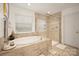 Bathroom featuring a soaking tub, glass enclosed shower, tile surround, and natural light from window at 3332 Delaware Dr, Denver, NC 28037