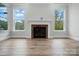 Bright living room features fireplace, hardwood floors, and two windows overlooking the outdoors at 4005 Grace Pointe Dr # 100, Wesley Chapel, NC 28079