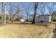 A spacious backyard featuring a gravel firepit area, mature trees, and a detached shed at 6706 Queensberry Dr, Charlotte, NC 28226