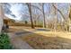 A spacious backyard featuring a gravel firepit area, mature trees, and a wood fence at 6706 Queensberry Dr, Charlotte, NC 28226