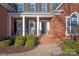 Brick front porch with columns, rocking chairs, and lush landscaping at 819 Lillieshall Rd, Waxhaw, NC 28173