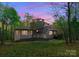 Unique exterior view of a charming home with natural landscaping surrounded by trees during the sunset at 10200 Amsterdam Dr, Mount Pleasant, NC 28124