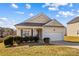 Tan house with a white garage door and landscaping at 124 Zolder Ln # 15, Mooresville, NC 28117