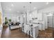 Open-concept kitchen with white cabinets, stainless steel appliances, island seating, and hardwood flooring at 3113 Beacon Heights Rd, Indian Land, SC 29707