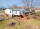 Back exterior of home featuring a raised wooden deck and sunroom with multiple windows for ample natural light at 3416 Polkville Rd, Shelby, NC 28150