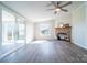 Cozy living room features a stone fireplace, ceiling fan, and access to the sunroom with sliding glass doors at 3416 Polkville Rd, Shelby, NC 28150