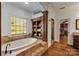 Elegant bathroom with soaking tub, walk-in shower, and built-in shelving at 6049 Bluebird Hill Ln, Weddington, NC 28104