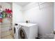 Functional laundry room equipped with a washer, dryer, and storage shelves for supplies at 1000 Weeping Willow Ln, Matthews, NC 28105