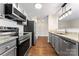 The kitchen features stainless steel appliances, granite counters, gray cabinets, and hardwood floors at 1620 #G Arlyn Cir # G, Charlotte, NC 28213