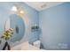 Small bathroom with blue walls, oval mirror, and toilet at 13010 Marlstone Ln, Charlotte, NC 28215