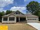 Beige house with brown accents, two-car garage, and a well-maintained yard at 305 General As Johnston St, Stanley, NC 28164