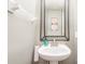 Small powder room with pedestal sink, stylish mirror, and neutral walls at 9729 Cockerham Ln, Huntersville, NC 28078