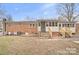 Home's backyard showcasing a brick exterior, a small deck, and an expansive, level lawn at 122 Lowry Row, York, SC 29745