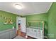 Bedroom with green walls, crib, and built-in shelving at 2714 Springway Dr, Charlotte, NC 28205