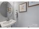 Small powder room with pedestal sink and circular mirror at 5033 Westmead Ln, Charlotte, NC 28262