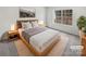 Virtually staged bedroom with large window and light wood bed frame at 6041 Pinebark Ct, Charlotte, NC 28212