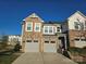 Modern two-story townhome with stone and siding accents, two-car garage, and landscaped lawn at 5860 Clan Maclaine Dr, Charlotte, NC 28278