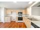 Charming kitchen with wooden cabinets, neutral countertop, black appliances, and hardwood floors at 8624 Woodcock Ln, Charlotte, NC 28216