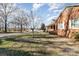 Side yard of brick house with trees and street at 107 E Boyd St, Maiden, NC 28650