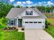 Charming home boasts a well-manicured lawn and inviting two-car garage, complemented by beautiful stone accents at 15298 Windward Ln, Lancaster, SC 29720