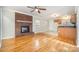 Living room with hardwood floors, brick fireplace, and kitchen at 2016 W Arrowood Rd, Charlotte, NC 28217