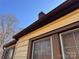 Close-up of house exterior shows yellow siding, brown trim, and a window with boarded-up glass at 3101 Dogwood Ave # 3, Charlotte, NC 28206