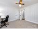 Cozy bedroom featuring paneled walls, ceiling fan, neutral carpet, and access to other rooms in the home at 4837 Holbrook Dr, Charlotte, NC 28212