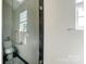 Glass-enclosed shower with neutral tile and a window at 8244 Fox Swamp Rd, Charlotte, NC 28215