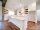 Modern white kitchen with a large island, floating shelves, and hardwood floors at 0000 Trull Hinson Rd, Wingate, NC 28174